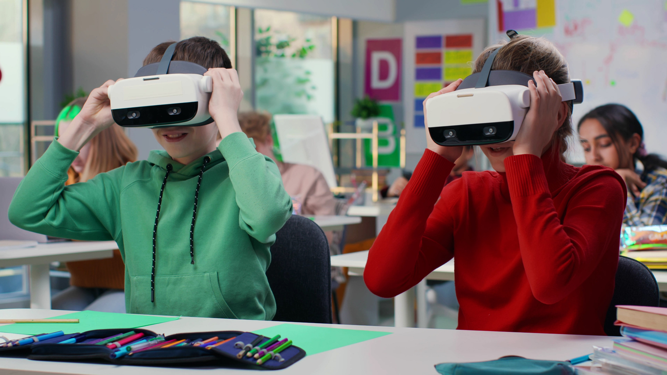 Portrait of schoolkids sitting at desk and putting on vr headset in classroom scuola e digitale